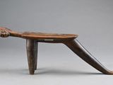 un vieux tabouret en bois muni d'une poignée en bois, sur fond gris