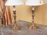 deux lampes posées sur une table, avec un rideau derrière elles