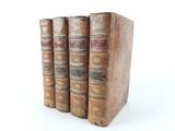 three old books sitting on top of each other on a white surface