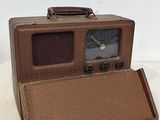 une vieille radio marron posée sur une table blanche