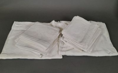several white towels are stacked on top of each other on a table