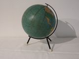 a small green globe on a stand on a white surface