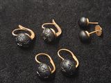 un lot de cinq boucles d'oreilles en pierre dorée et noire, posées sur un fond noir