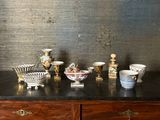 de nombreux vases et coupes de toutes sortes posés sur une commode