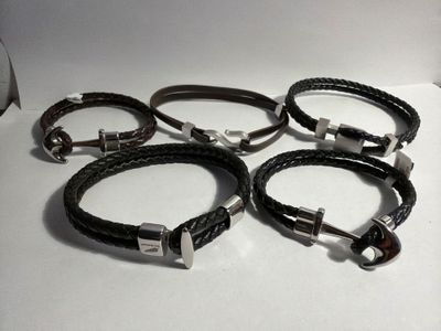 six black leather bracelets with silver clasps on a white surface