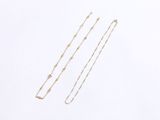 two gold necklaces on a white surface with a white background