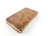 an old book sitting on top of a table on a white surface