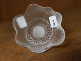 un petit objet en forme de fleur blanche posé sur une table en bois