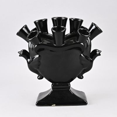 un vase noir posé sur un socle, contenant cinq tasses