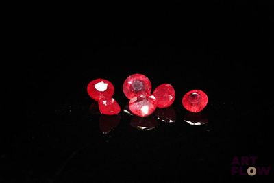some very pretty red diamonds sitting on top of a black surface
