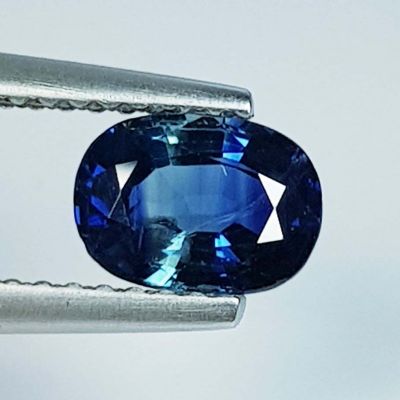 un gros plan d'un saphir bleu tenu par une paire de pinces