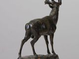 bronze statue of a stag on a rock on a white surface