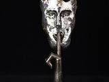 une sculpture en argent représentant une tête de chat, posée sur un socle métallique