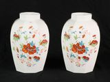 pair of white vases with floral designs on them against a black background