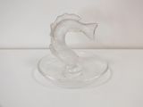 a glass seahorse on a glass plate on a white surface