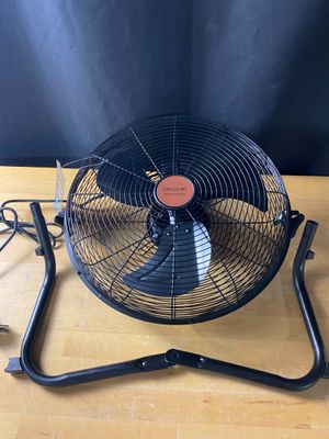 un ventilateur électrique posé sur une table en bois près d'un mur
