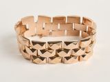 gros plan d'un bracelet en or sur une surface blanche