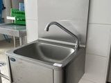a stainless steel sink in the middle of a tiled floor