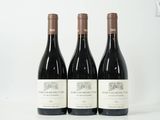 trois bouteilles de vin rouge sont posées sur une surface blanche