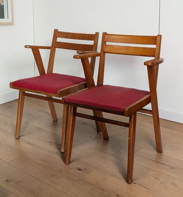 Deux chaises en bois, dotées de coussins rembourrés rouges, sont posées sur un parquet en bois massif.