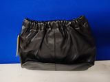 a black purse sitting on top of a table next to a blue wall