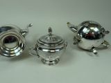 two silver teapots and a silver teapot on a table
