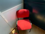 a red chair sitting in front of a window in a room
