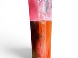 a pink and orange vase sitting on a white surface