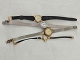 three different watches are sitting on a table with a white background