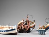 three figurines of people on a boat and a man on a boat