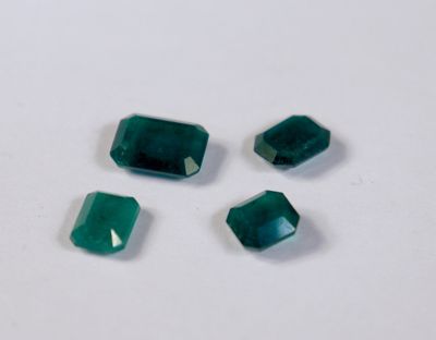 un groupe de quatre pierres précieuses vert émeraude sur un fond blanc