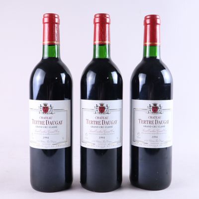 trois bouteilles de vin rouge posées l'une à côté de l'autre sur une surface blanche