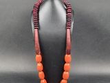 un collier composé de perles orange sur un mannequin noir