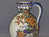 un vase blanc muni d'une anse bleue posé sur une table