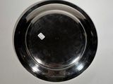 a silver plate on a white surface with a small diamond on it