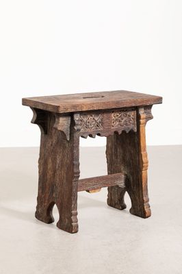 une vieille table en bois dont le plateau sculpté repose sur un plan de travail blanc