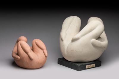 deux sculptures en céramique représentant des mains et des pieds, posées sur un socle noir