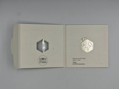 a silver coin in a white box on a table