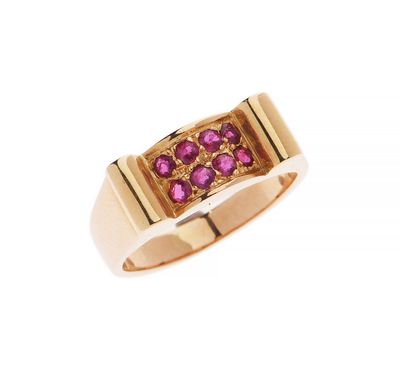 un gros plan d'une bague en or sertie de pierres roses sur fond blanc