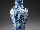 blue and white vase on a gray surface with a black background