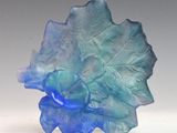 a blue glass sculpture of a leaf on a white surface