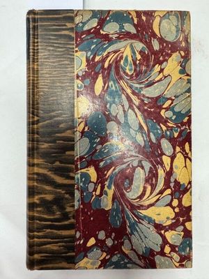 un vieux livre à la couverture en bois posé sur une table blanche