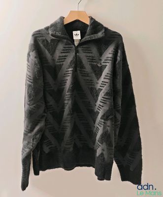 a black sweater hanging on a wall next to a hanger