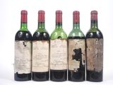 quatre bouteilles de vin sont alignées sur une surface blanche
