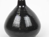 a black vase that is sitting on a white surface