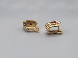 a pair of gold earrings with a ruby stone