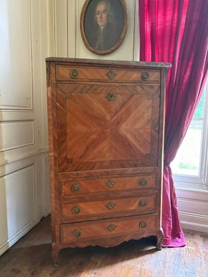 une commode dans une pièce où est accroché un tableau au mur