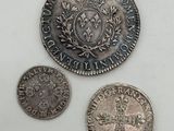 three silver coins sitting next to each other on a white surface