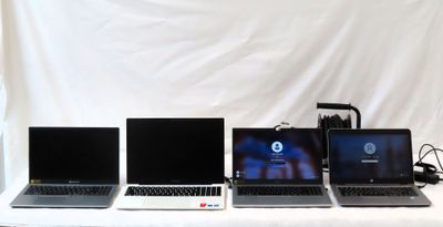 four laptops are lined up on a table with a white backdrop