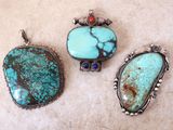 trois pendentifs ornés de turquoises et de pierres rouges, posés sur une table